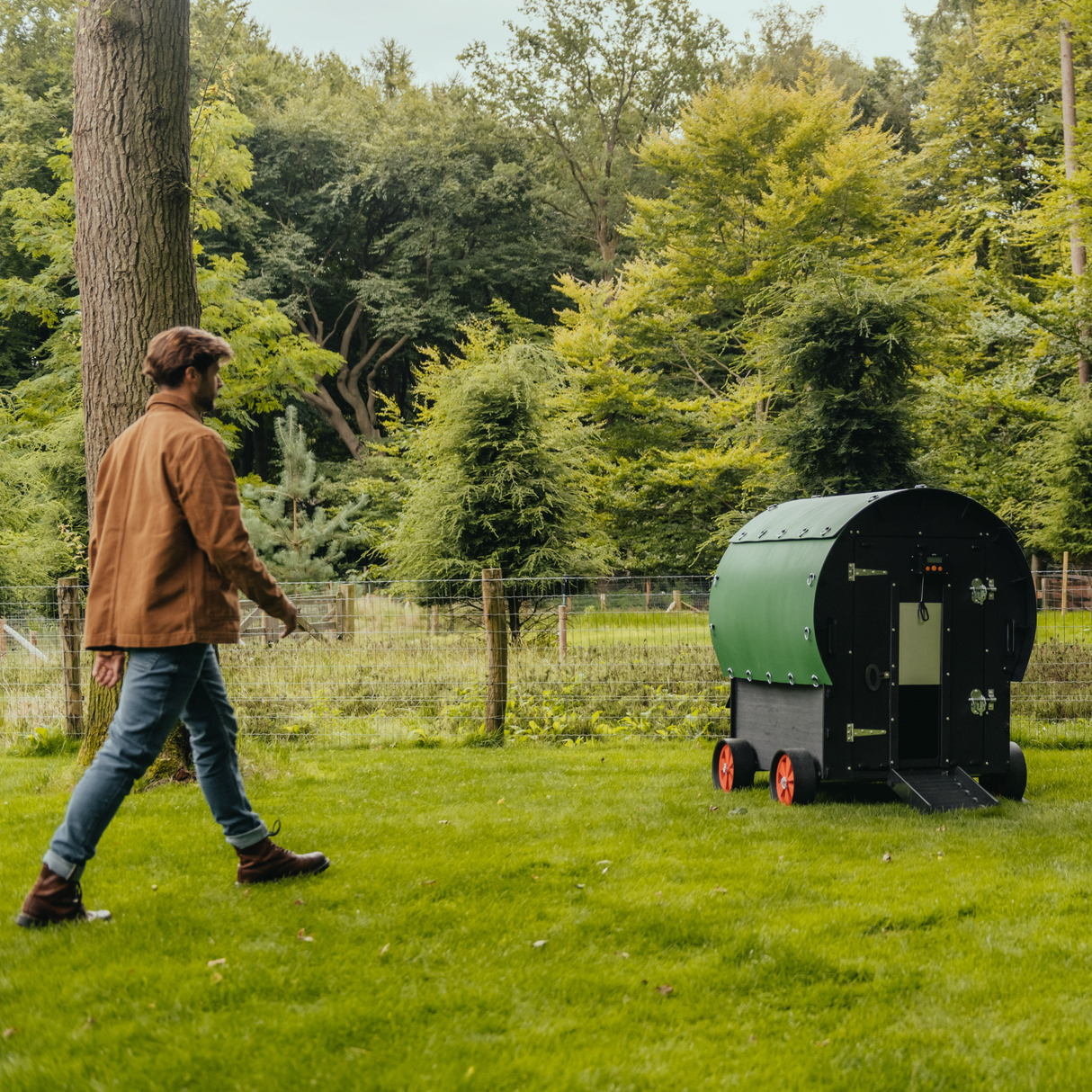 Hatching Time Nestera. Image shows a man walking towards the Nestera Chicken coop Wagon to show size scale.