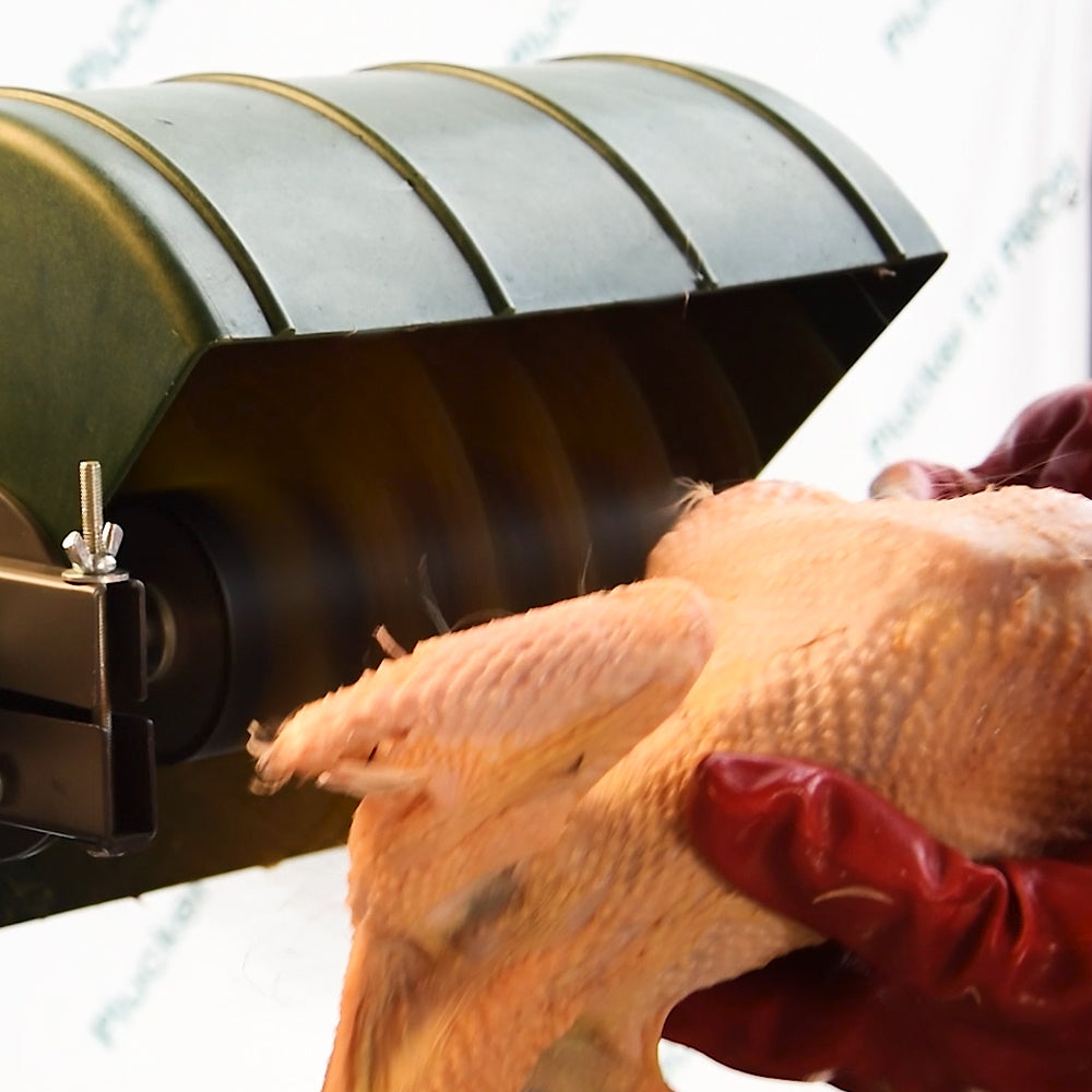 Close-up of drill-powered feather plucker removing feathers from a chicken, showing motion blur of yellow rubber fingers inside protective green housing
