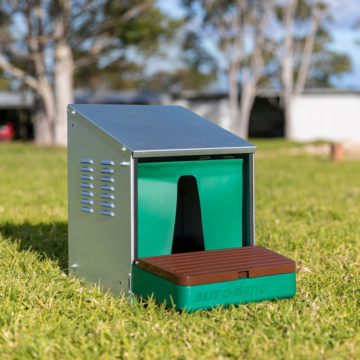 a Nest-O-Matic Roll Out Nesting Box sitting in the grass outside