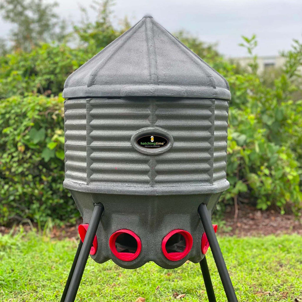 a Silo Feeder (80 lb) sitting outside with trees behind it