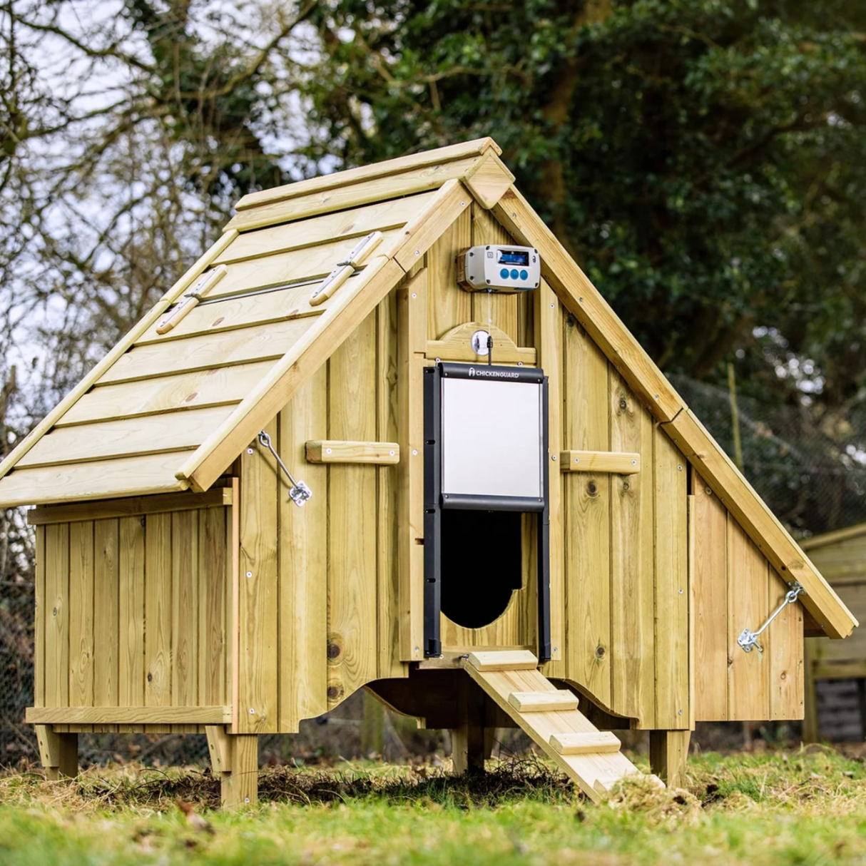 Hatching TIme. ChickenGuard Pro with Self-Locking Door Kit shown installed on chicken coop on grass.