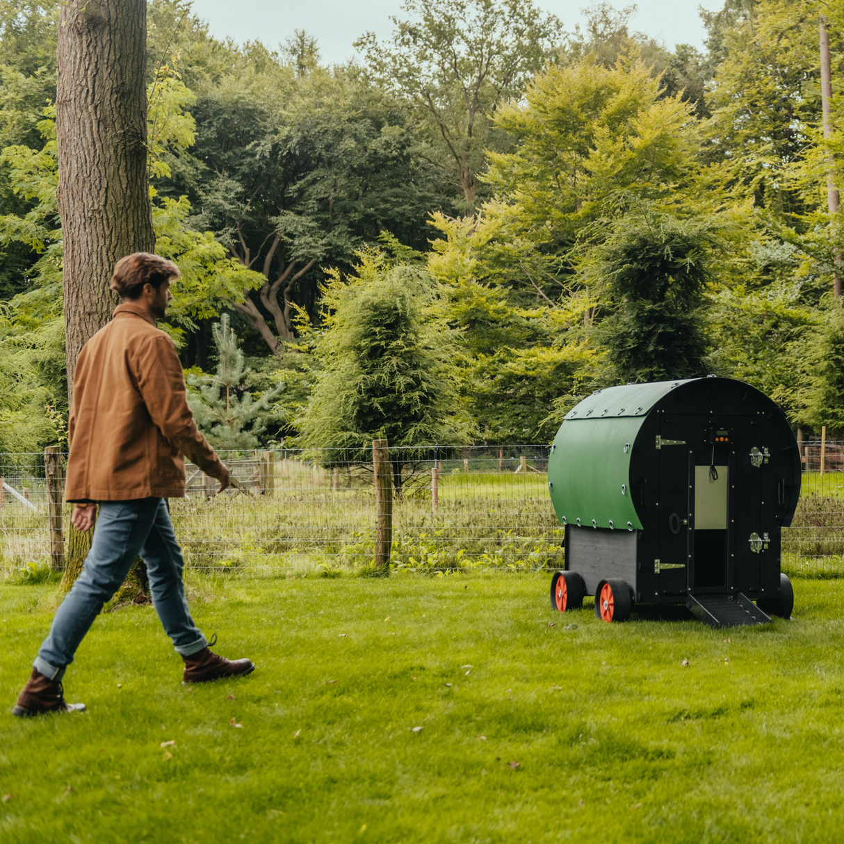 Hatching Time Nestera. Image shows a man walking towards the Nestera Chicken coop Wagon to show size scale. 