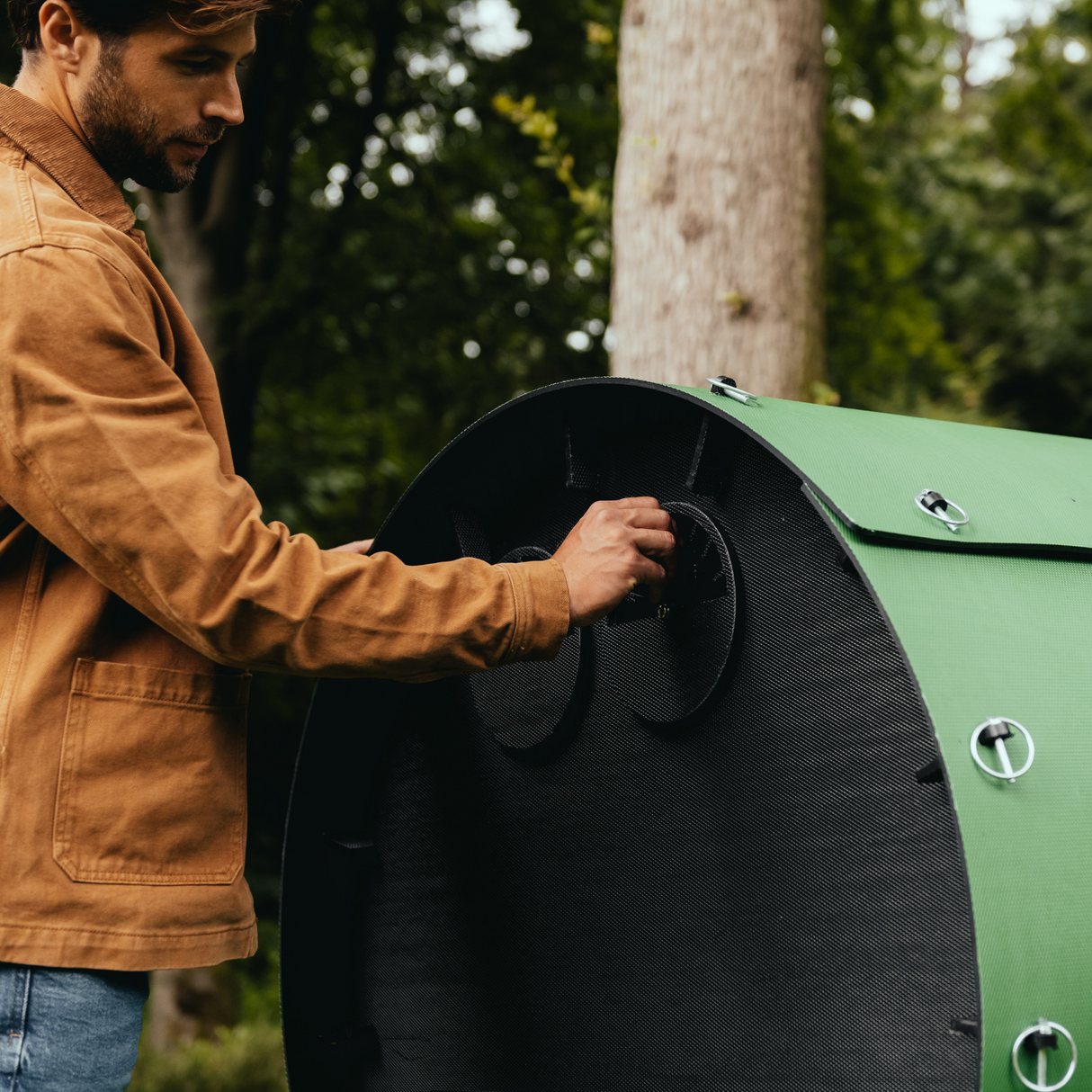 Hatching Time Nestera. Image shows a man opening air ports in rear of Nesterat chicken coop Wagon. Adjustable air flow allows for warmer temperatures inside during the winter and cooling off in the summer for chicken comfort.