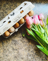 Hatching Time Henlay Egg Carton pre-marked with free range, hand gathered, farm fresh and laid local branding on countertop next to tulips.