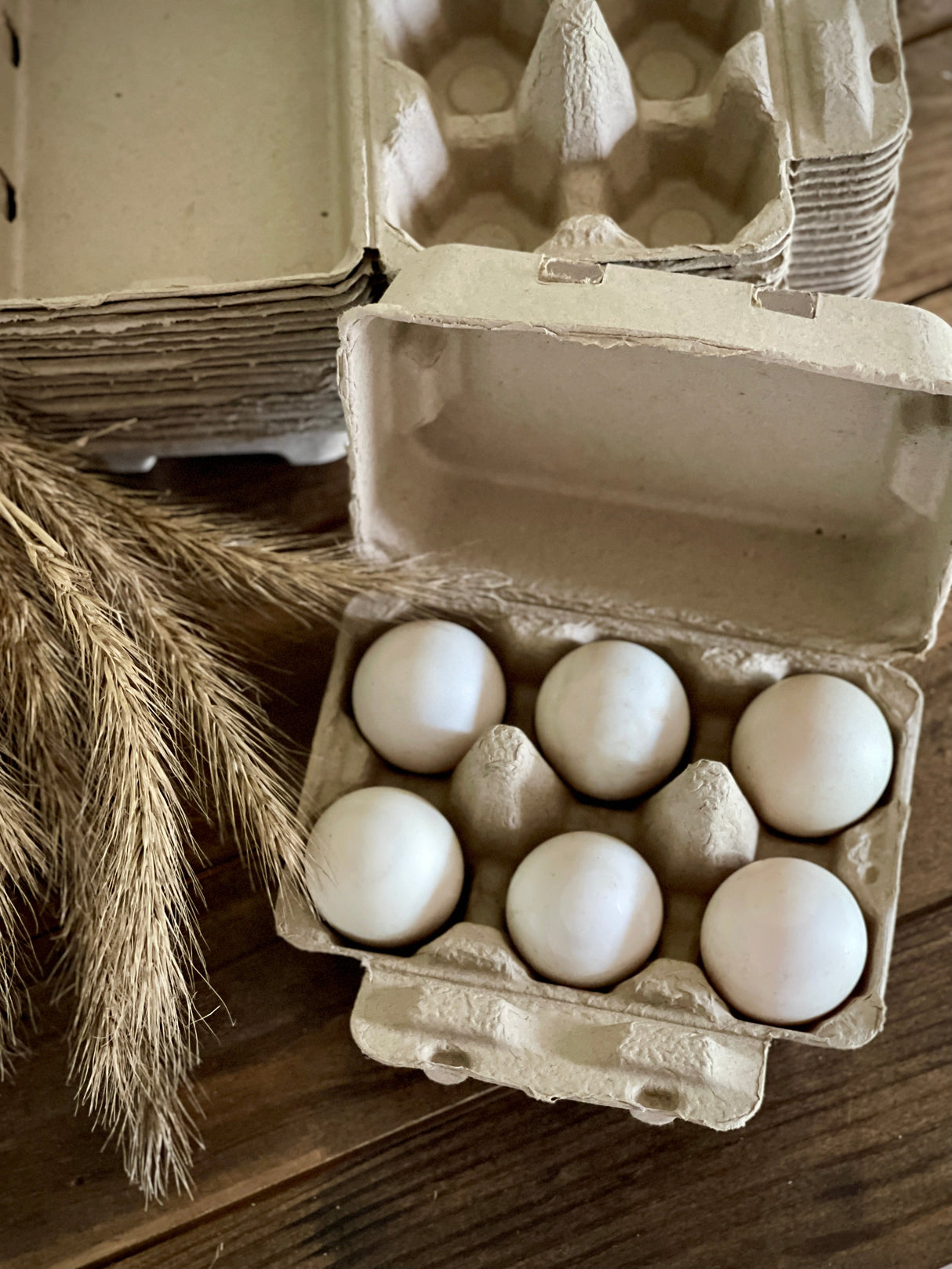 Eggs in natural egg carton on table by wheat.