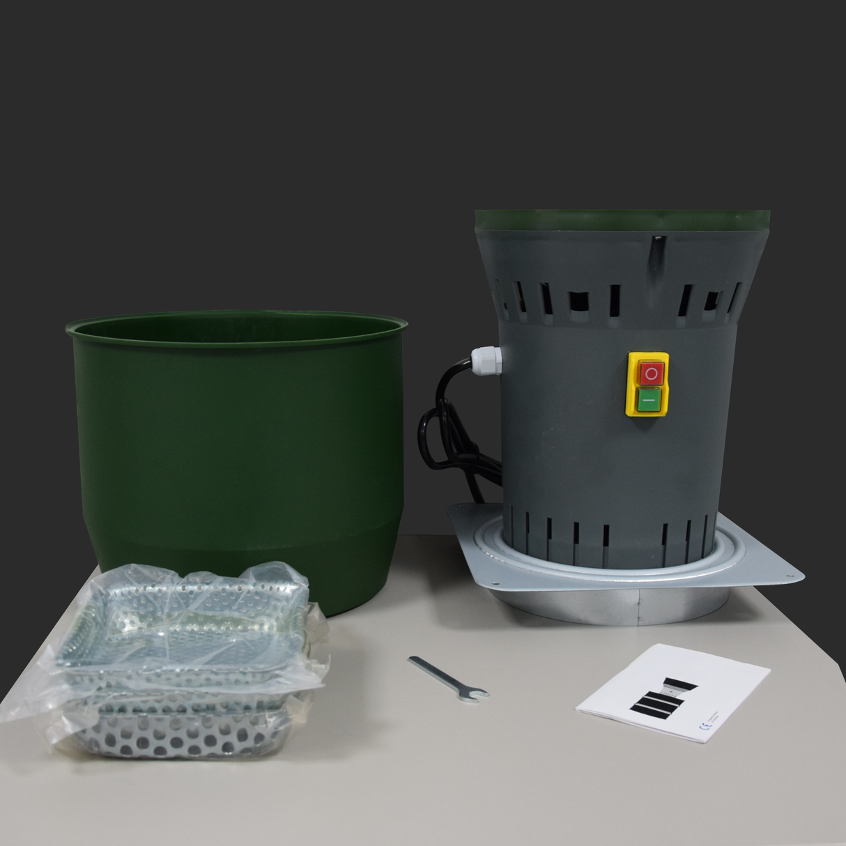 Farm Mill Compact Feed Crusher full kit showing green hopper, gray motor base with power switch, perforated grinding screen, wrench, and user manual on table