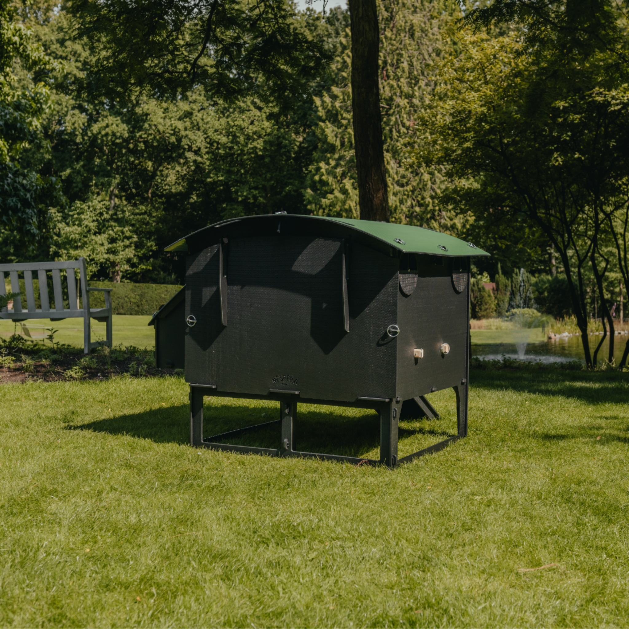 Hatching Time Nestera. Rear view large Lodge coop can be seen in image on grass. Nesting box is on side connected to chicken coop, with lifting door for easy egg access. Roof of coop is slanted to prevent roosting.