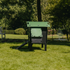 Hatching Time Nestera. Side view of Small Lodge coop can be seen in image on grass. Ramp is leading up to opening for easy chicken access. Nesting box is on side connected to chicken coop, with lifting door for easy egg access. Roof of coop is slanted to prevent roosting.