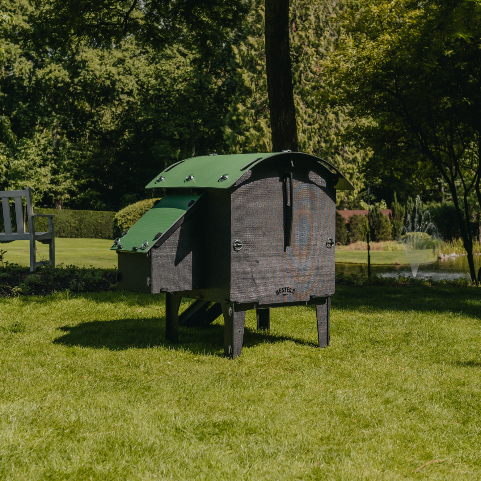 Hatching Time Nestera. Rear view Small Lodge coop can be seen in image on grass. Nesting box is on side connected to chicken coop, with lifting door for easy egg access. Roof of coop is slanted to prevent roosting.