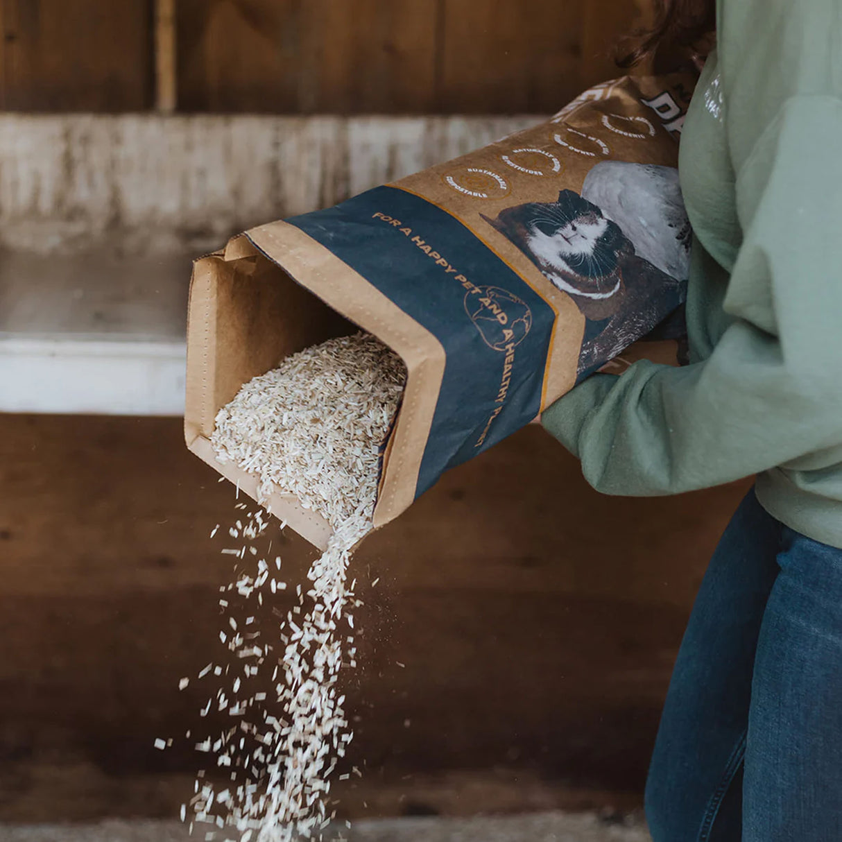 Naturally Grown Premium Hemp Pet Bedding being poured from a 33 lb bag, showing the natural hemp bedding texture and particle size.