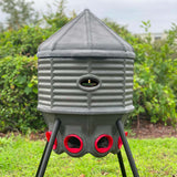 a Silo Feeder (80 lb) sitting outside with trees behind it