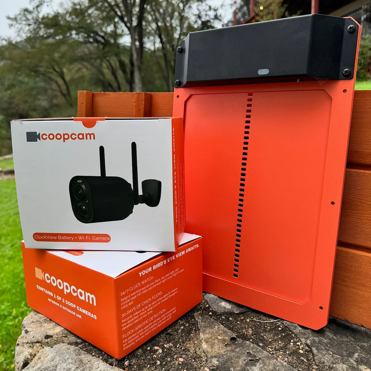 Coopcam outdoor security camera and packaging on a stone surface with a natural background