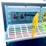 Hatching Time Cimuka Open door on 9.5" Grow out pen shows interior floorplan with drinker cups mounted on back wall of grow out pen. Feeding trough with cover is on front of the pen.