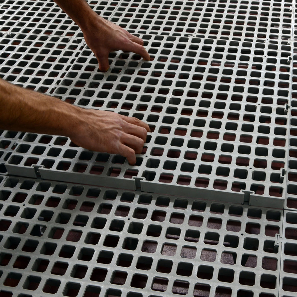 Hatching Time Cimuka. Hands placing Large Hole slat flooring together.
